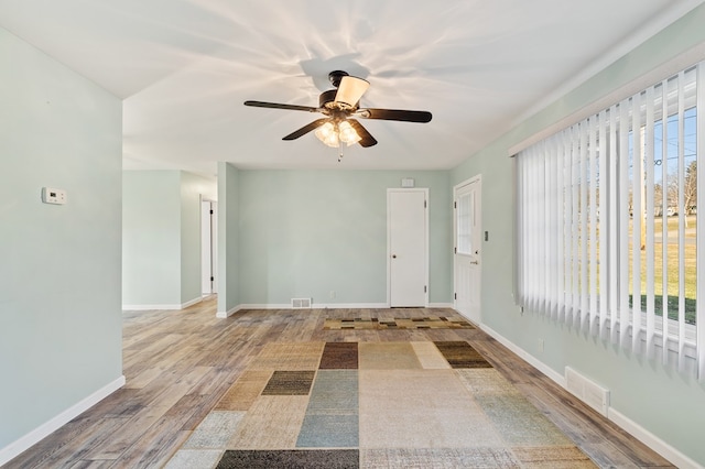 spare room with ceiling fan, wood finished floors, visible vents, and baseboards