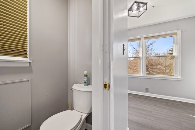 bathroom with toilet, wood finished floors, and baseboards