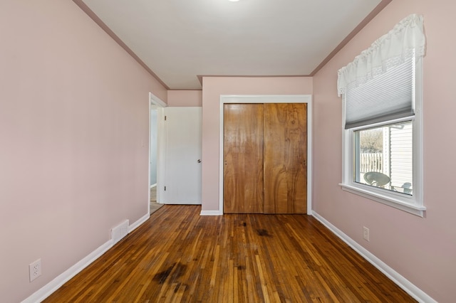 unfurnished bedroom featuring hardwood / wood-style floors, crown molding, and baseboards