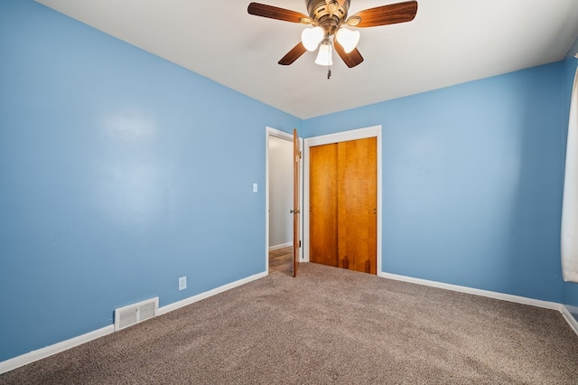 carpeted spare room with visible vents, baseboards, and ceiling fan