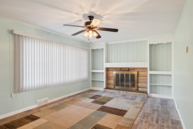 unfurnished living room with visible vents, ceiling fan, baseboards, a fireplace, and wood finished floors