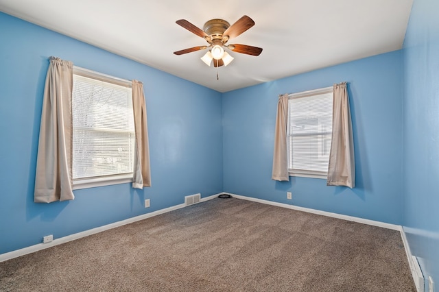 carpeted spare room with visible vents, plenty of natural light, baseboards, and a ceiling fan