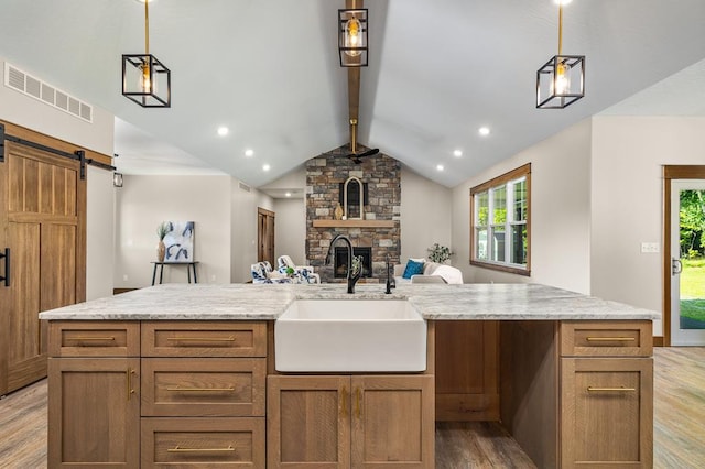 kitchen with pendant lighting, a barn door, an island with sink, and sink