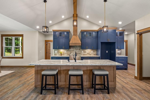 kitchen featuring blue cabinetry, pendant lighting, and a center island with sink