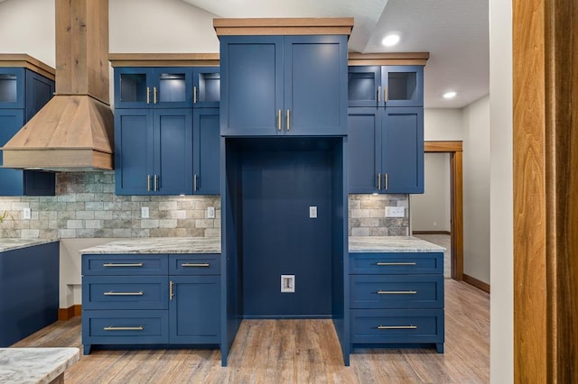 kitchen featuring backsplash, light stone countertops, blue cabinets, and light wood-type flooring