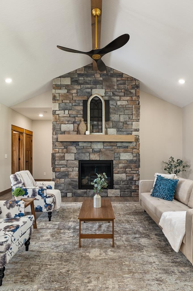 living room featuring a stone fireplace, ceiling fan, and lofted ceiling