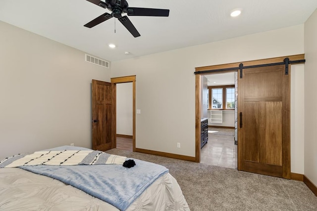 bedroom with a barn door, light colored carpet, and ceiling fan