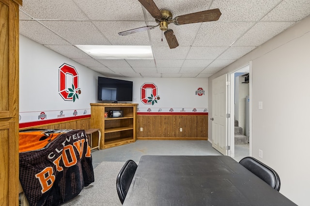 playroom featuring wooden walls, ceiling fan, and a paneled ceiling