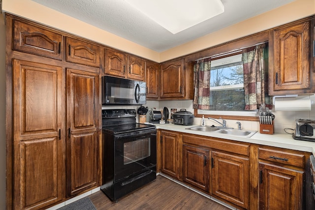 kitchen with dark hardwood / wood-style floors, sink, a textured ceiling, and black appliances