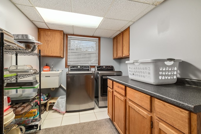 clothes washing area with sink, washer and clothes dryer, cabinets, and light tile patterned flooring