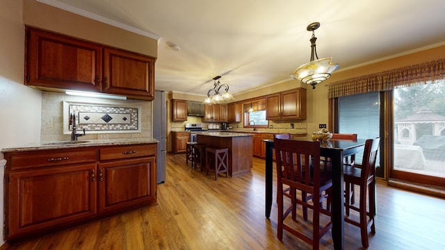 dining area with a chandelier, ornamental molding, and light wood finished floors