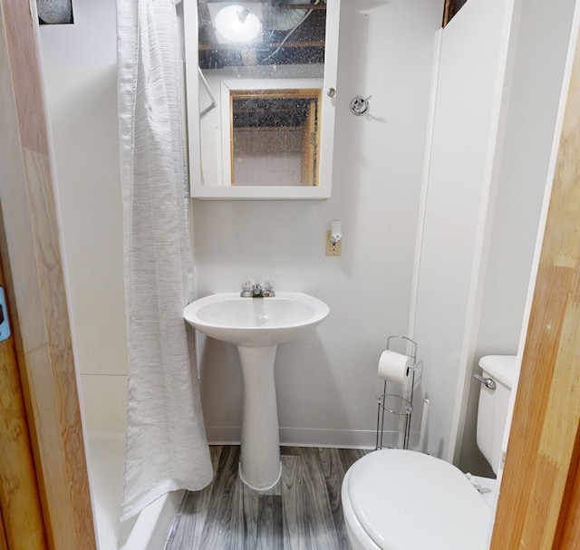 full bathroom featuring toilet, curtained shower, baseboards, and wood finished floors