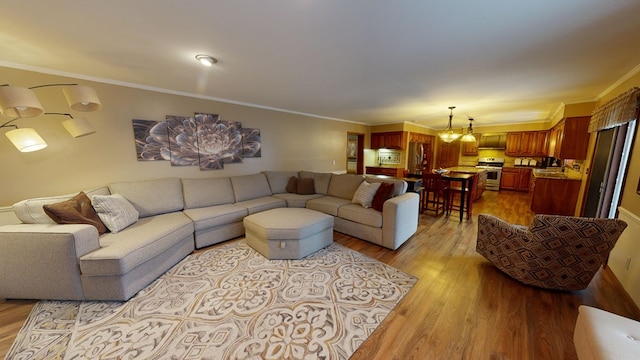 living area with a chandelier, crown molding, and wood finished floors