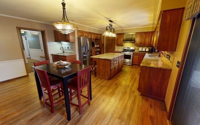 kitchen with wall chimney range hood, appliances with stainless steel finishes, a center island, and a sink