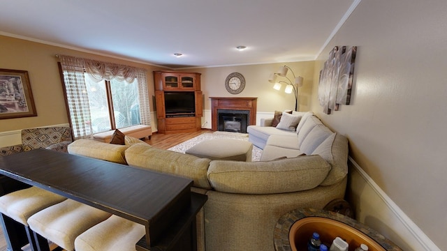living area featuring crown molding, a fireplace with flush hearth, and light wood-type flooring