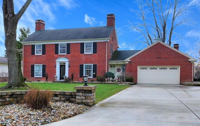 colonial-style house featuring a chimney, driveway, brick siding, and a garage