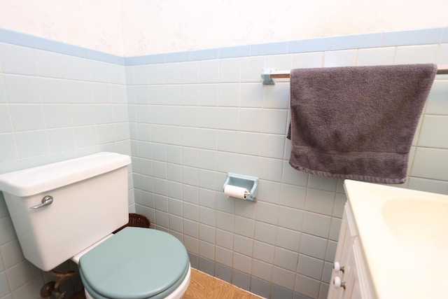 bathroom with toilet, vanity, and tile walls