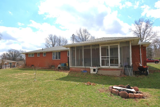 back of property featuring a lawn, a sunroom, fence, and brick siding