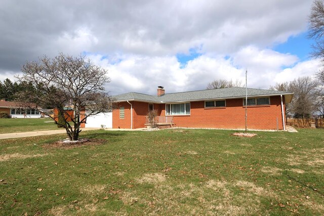ranch-style house featuring concrete driveway, an attached garage, a front lawn, brick siding, and a chimney