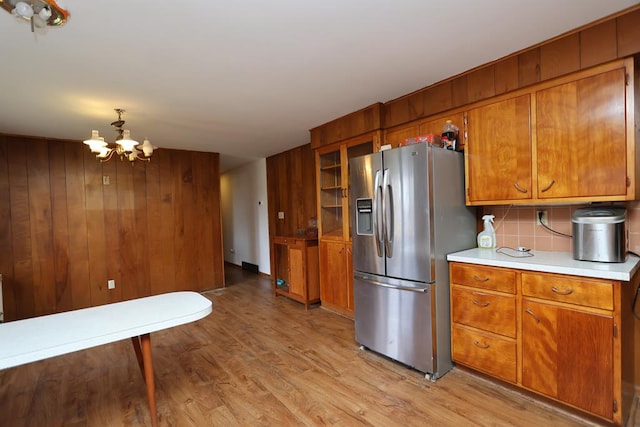 kitchen with light countertops, stainless steel fridge, a chandelier, light wood finished floors, and brown cabinets
