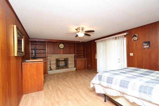 bedroom featuring wood walls, light wood-style floors, a fireplace, and baseboard heating