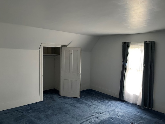 bonus room with lofted ceiling and dark carpet