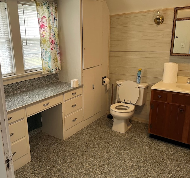 bathroom with vanity, wooden walls, and toilet