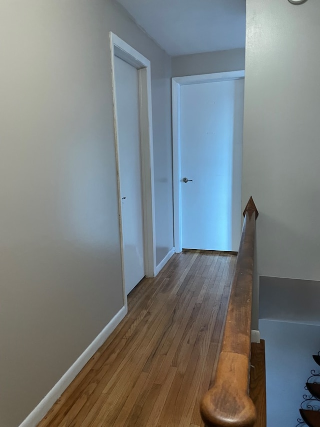corridor featuring baseboards and hardwood / wood-style floors