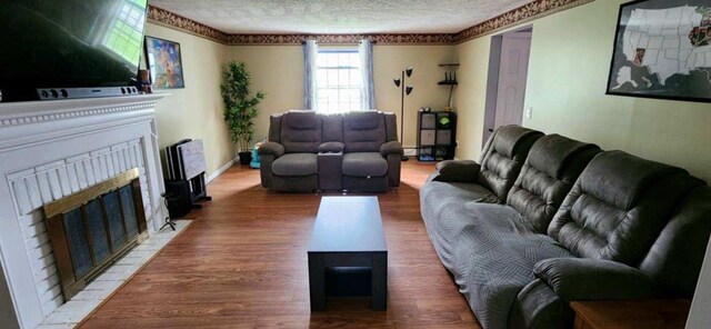 living room with wood finished floors, a textured ceiling, and a fireplace