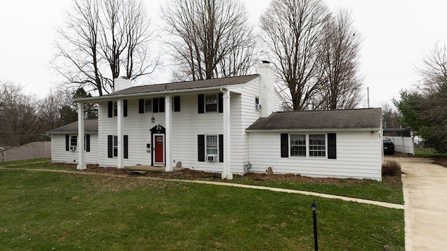 view of front of home featuring driveway, a chimney, and a front yard