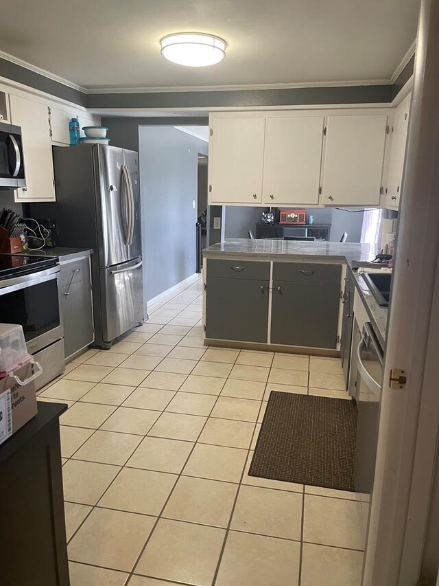 kitchen with white cabinetry, stainless steel appliances, light tile patterned flooring, and crown molding