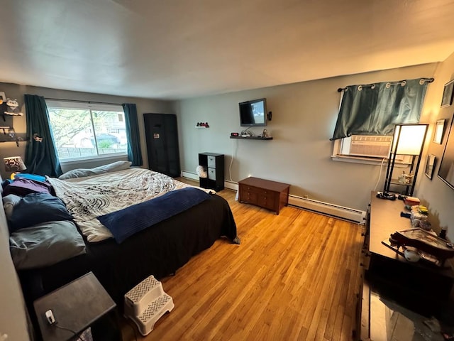 bedroom featuring a baseboard radiator, light wood-type flooring, and a baseboard heating unit