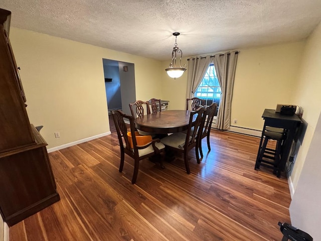 dining space featuring a textured ceiling, dark wood-style flooring, and baseboards