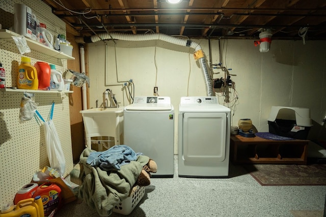 laundry room with washing machine and clothes dryer, a sink, and laundry area