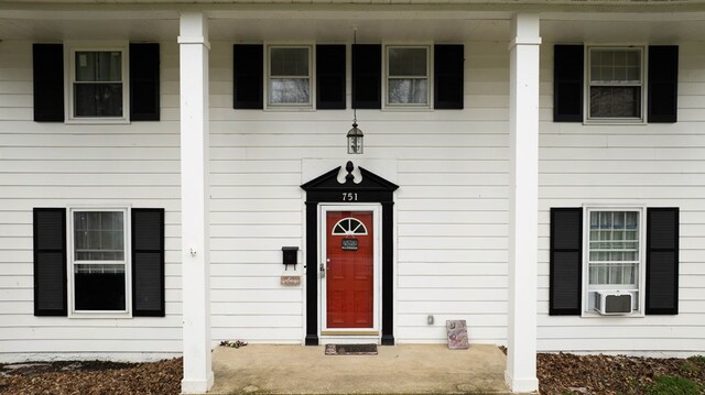entrance to property with a porch and cooling unit
