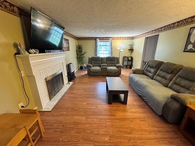 living area with a fireplace, a textured ceiling, and wood finished floors