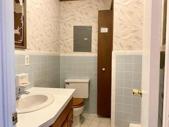 bathroom with tile patterned floors, vanity, tile walls, electric panel, and toilet