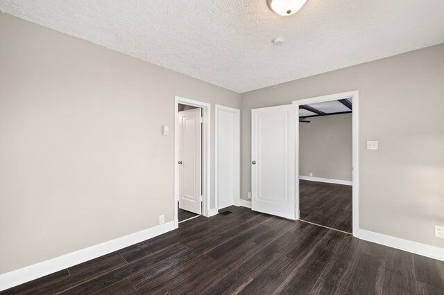 459 Glessner Ave, Mansfield, OH 44903 - unfurnished bedroom featuring dark wood finished floors, baseboards, a textured ceiling, and a closet