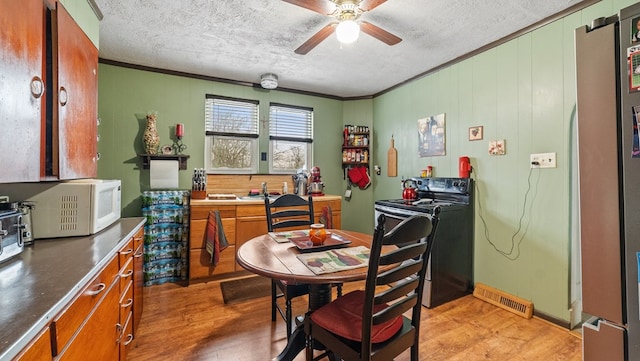 dining space featuring crown molding, a textured ceiling, ceiling fan, and light hardwood / wood-style flooring