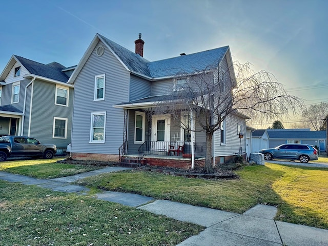 view of front of home featuring covered porch, a chimney, and a front lawn