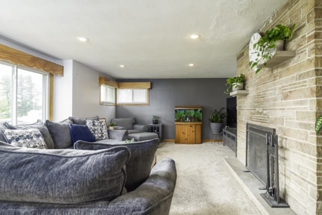 living room with a stone fireplace and light colored carpet