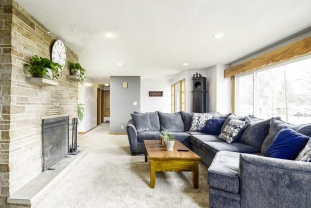 carpeted living room with a stone fireplace