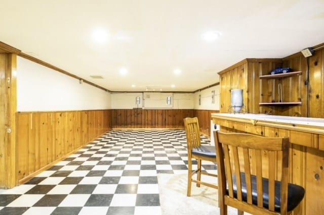 kitchen with a breakfast bar, wooden walls, and crown molding