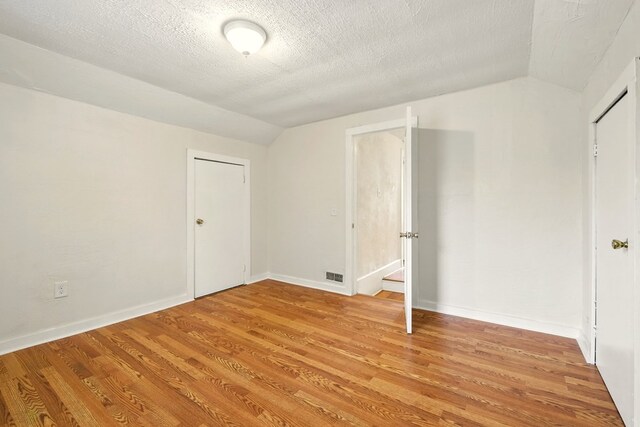 411 Grace St, Mansfield, OH 44902 - unfurnished bedroom with vaulted ceiling, light wood finished floors, baseboards, and a textured ceiling