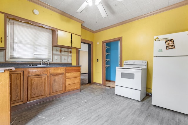 kitchen featuring white appliances, brown cabinetry, dark countertops, crown molding, and a sink