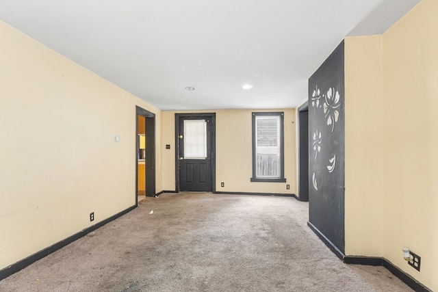 empty room featuring light carpet and baseboards