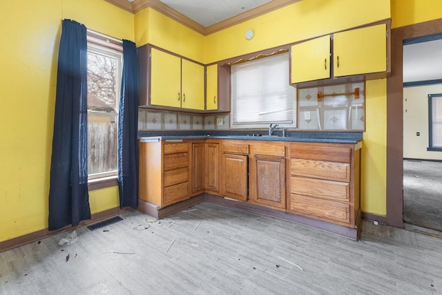 kitchen featuring dark countertops, a healthy amount of sunlight, visible vents, and crown molding