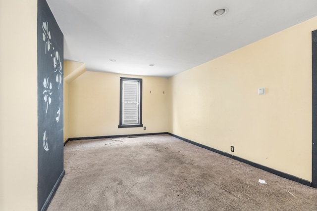 unfurnished room with baseboards, vaulted ceiling, and light colored carpet