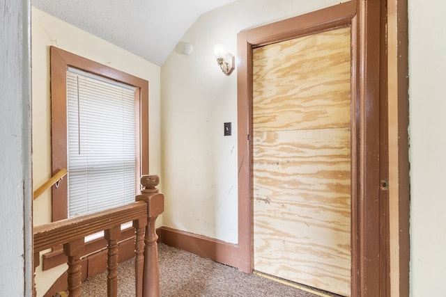 corridor featuring carpet floors, a textured ceiling, and lofted ceiling