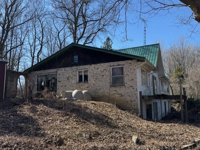 view of side of home with brick siding and metal roof